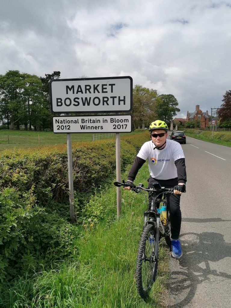 man with glasses on a bike next to a sign