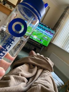 man watching rugby with a water bottle