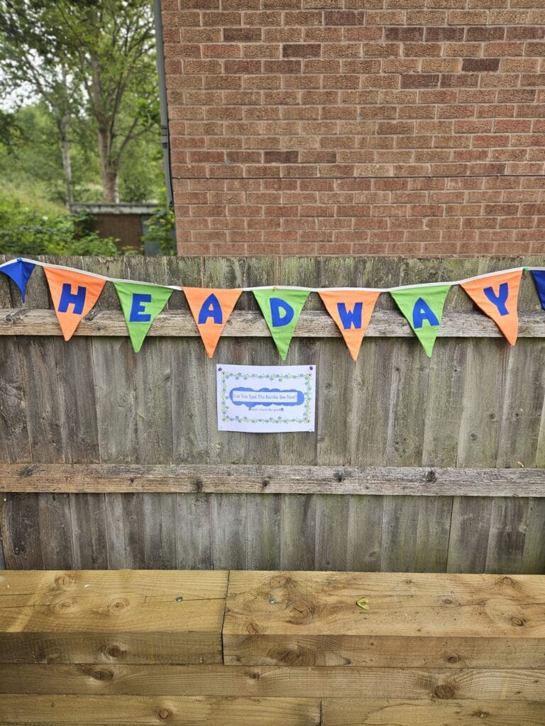 Headyway Summer Open day 2025. A picture of green and orange bunting spelling out "Headway" attached to a fence